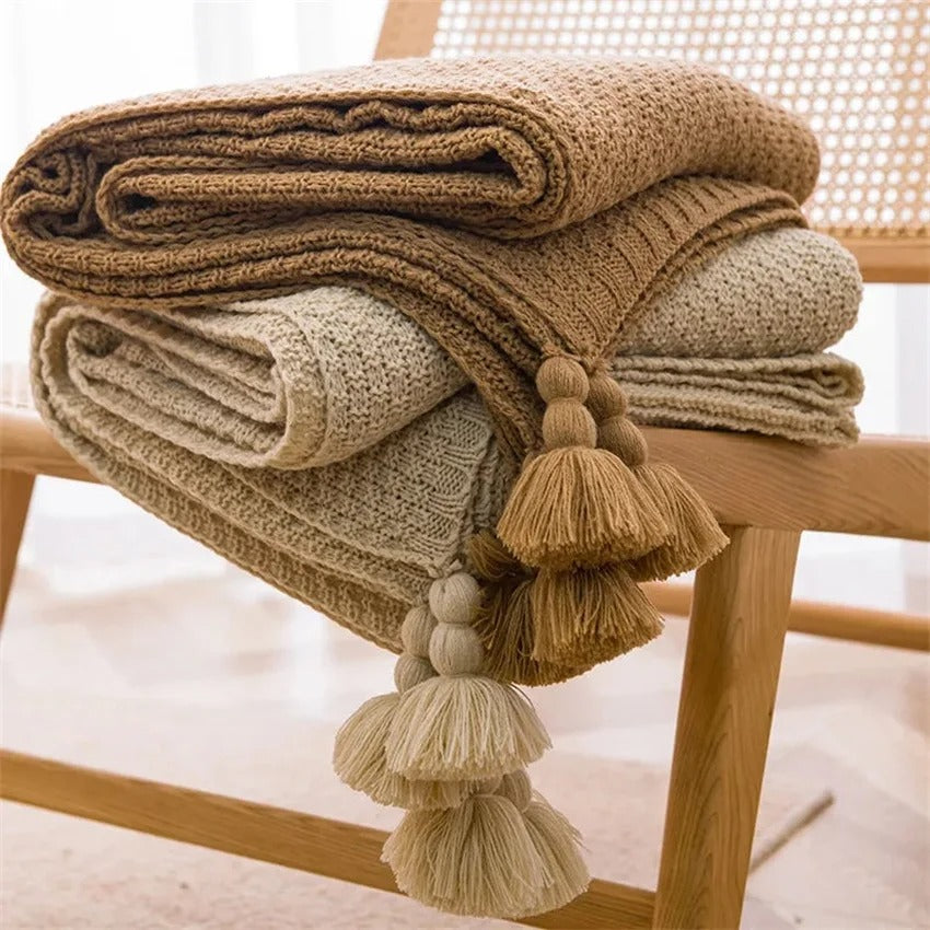 Couverture tricot pompon nordique pliees sur chaise